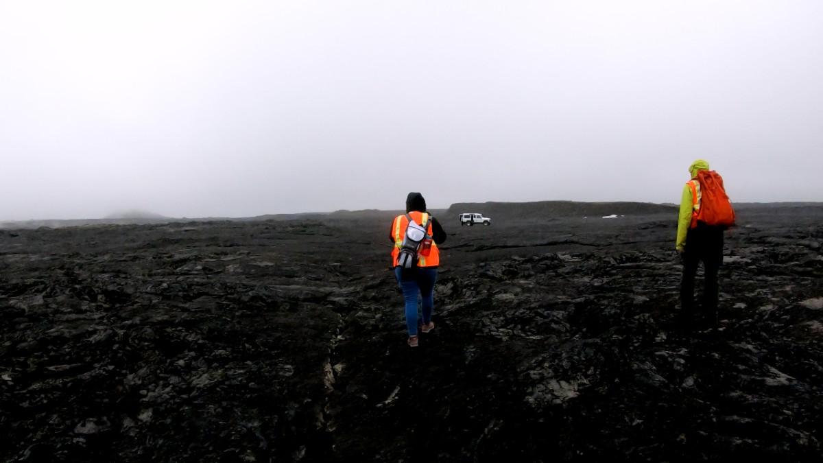 研究er walks across black Icelandic lava flow.