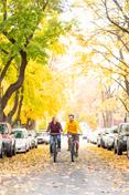 两个学生骑在希腊街在秋天，在树叶的变化.